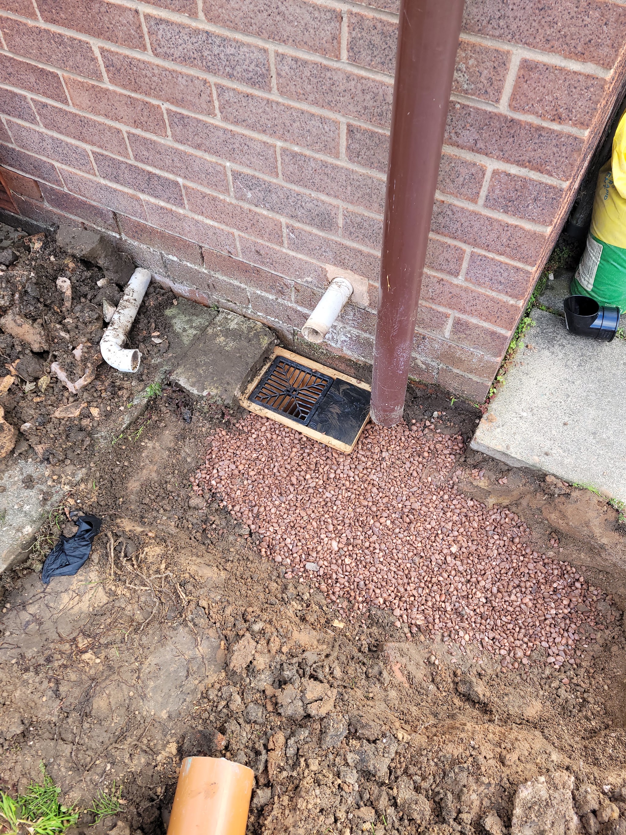 A new gully, fresh gravel and pipework at the foot of a house wall